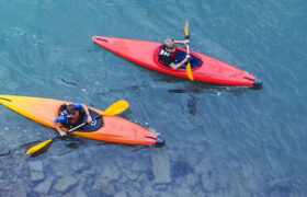 an aerial shot of two people in two kayaks on a lake shore